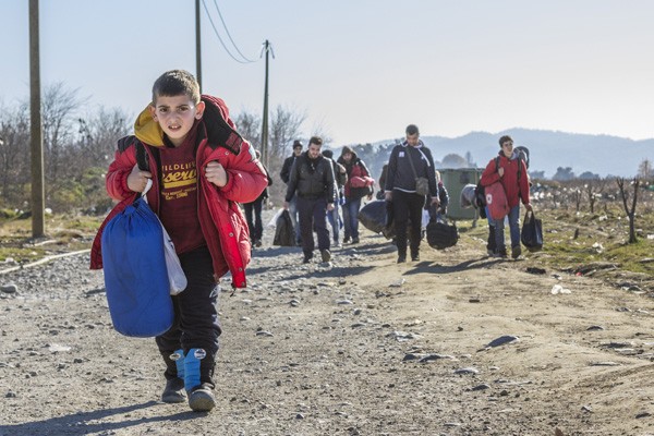 Young boy carrying a sleeping bag walking on a dirt road