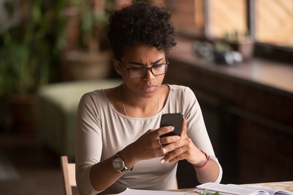Young woman with a pensive look on her cell phone